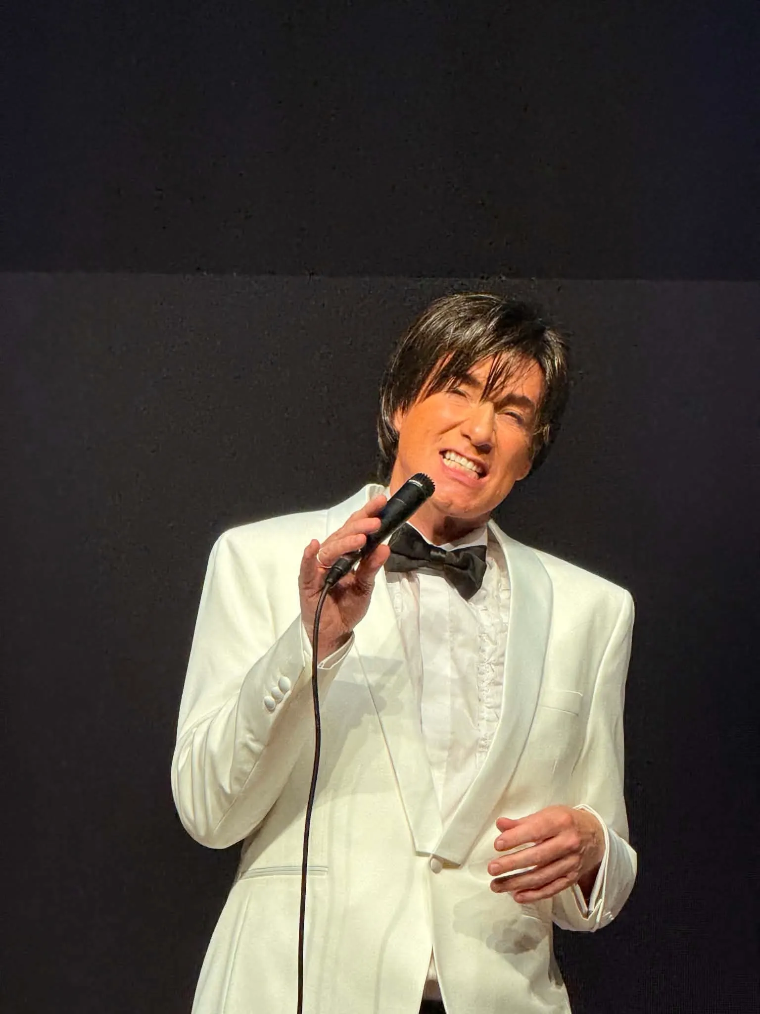 Sam Stevens singing in a white tuxedo