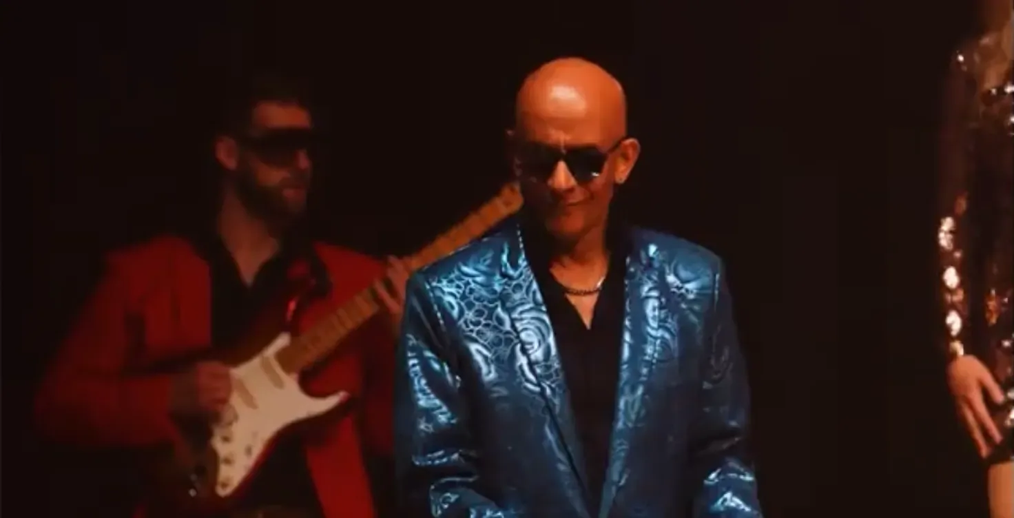 Keyboard player in a teal brocade jacket beside a guitarist in red