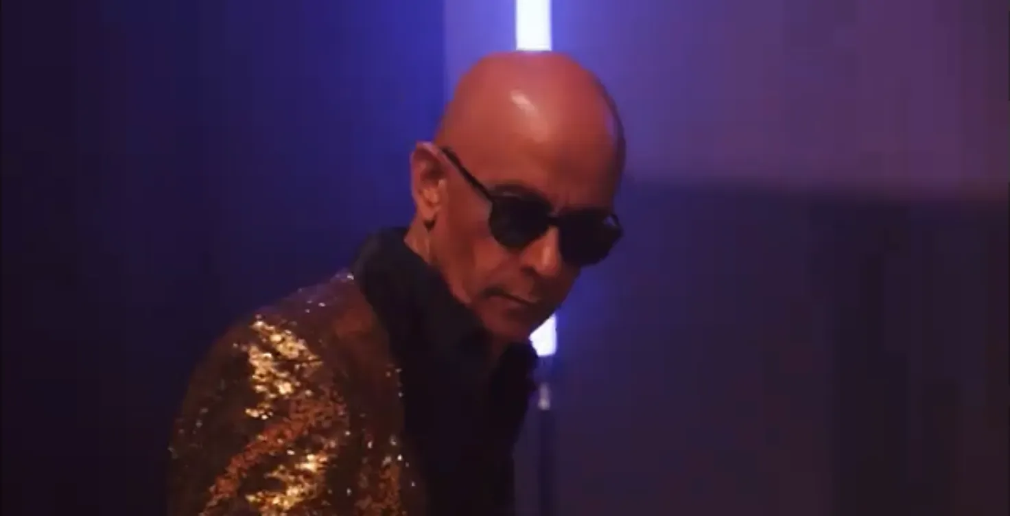 Keyboard player in a gold sequin jacket and dark glasses