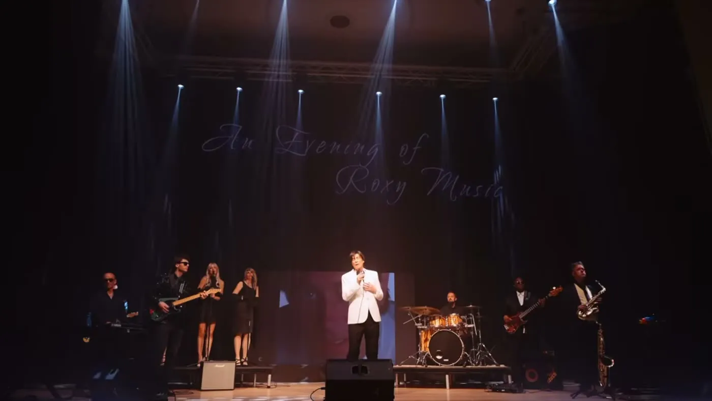 Sam Stevens in a white jacket centre stage with the band